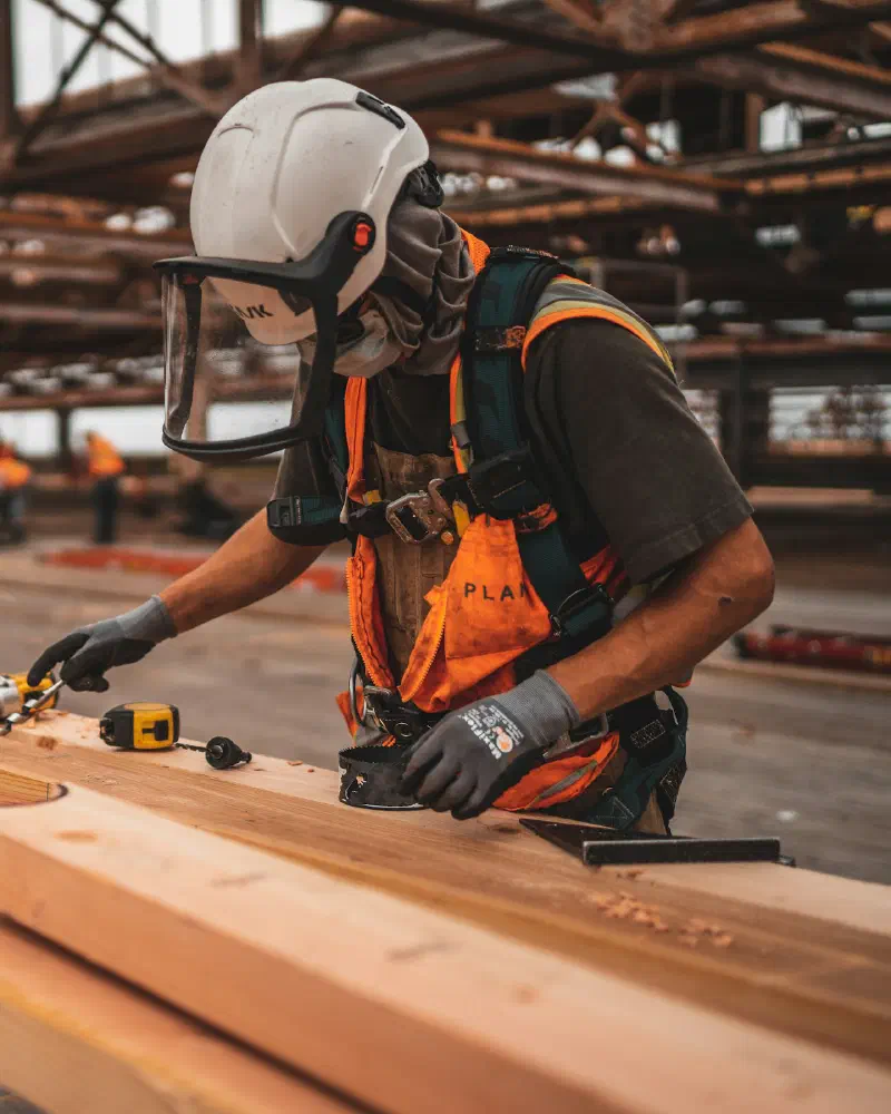 A carpenter measuring timber on a building site