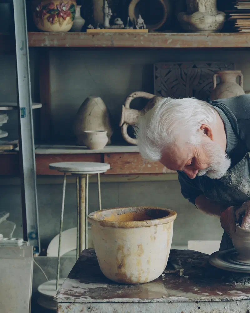 A potter shaping clay at the wheel in a workshop
